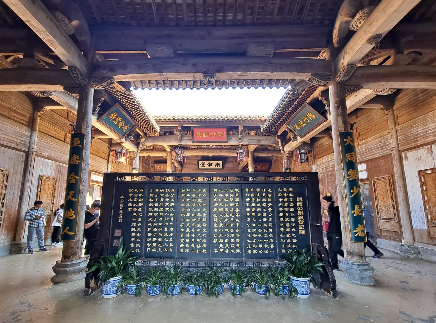 乐叙堂内部木构厅堂，中央立有宗族文字展板，两侧梁柱悬挂匾额与楹联